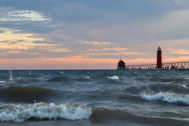 Violent Lake Michigan waves crashing against Grand Haven pier and red lighthouse — West Michigan Web services background